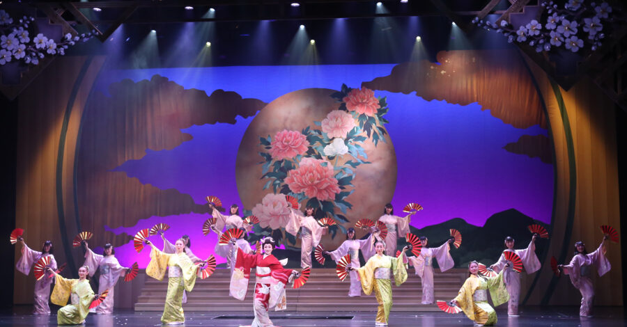 Performers in traditional Japanese dress on a large stage.