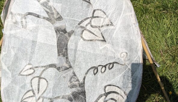 A hand-crafted paper lantern lying on the grass.