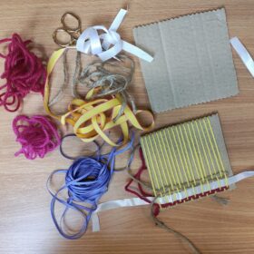 Table with craft materials, including wool and paper.
