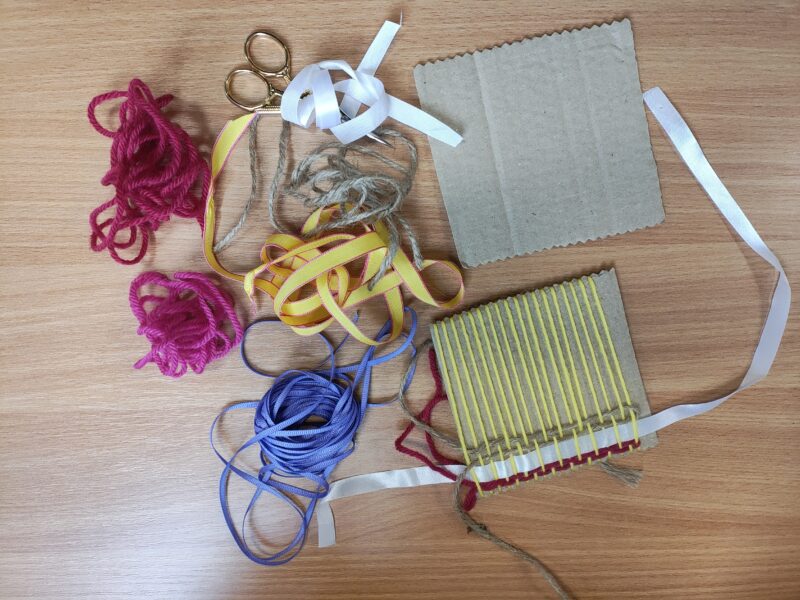 Table with craft materials, including wool and paper.