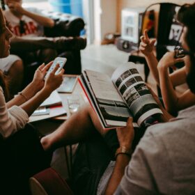 A group of people sitting on chairs reading books and sharing.