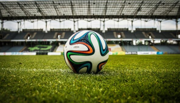A football in the middle of a grassy football pitch.