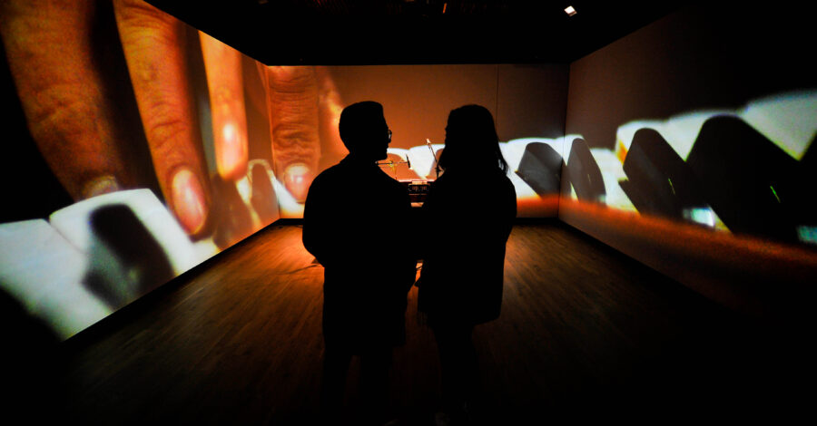 People watch a film within the performance space in Manchester Museum's South Asia Gallery.