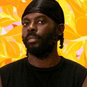 The artist Tunji Adeniyi-Jones wearing a black vest and a durag, stood in front of one of his artworks.
