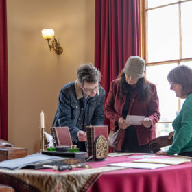 Volunteer engaging with visitors in a Victorian room.