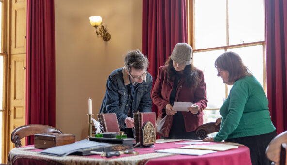 Volunteer engaging with visitors in a Victorian room.