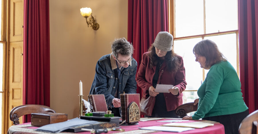 Volunteer engaging with visitors in a Victorian room.