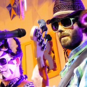 A close-up of two members of Rockin' Rhinos playing their musical instruments on stage.