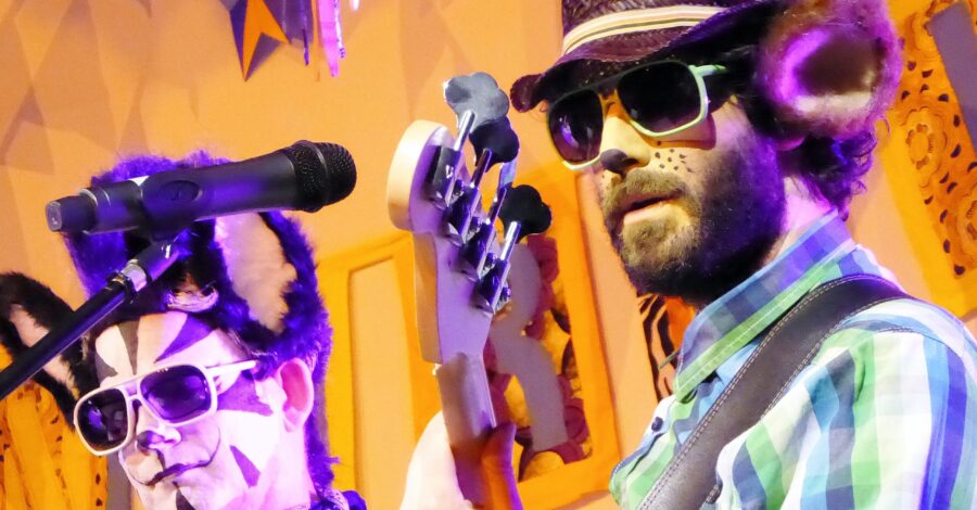 A close-up of two members of Rockin' Rhinos playing their musical instruments on stage.