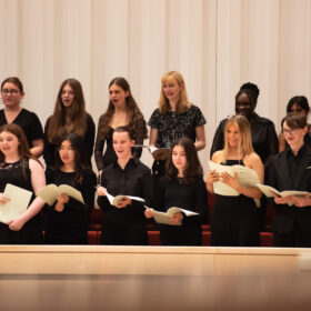 A group of young people dressed in black, singing.