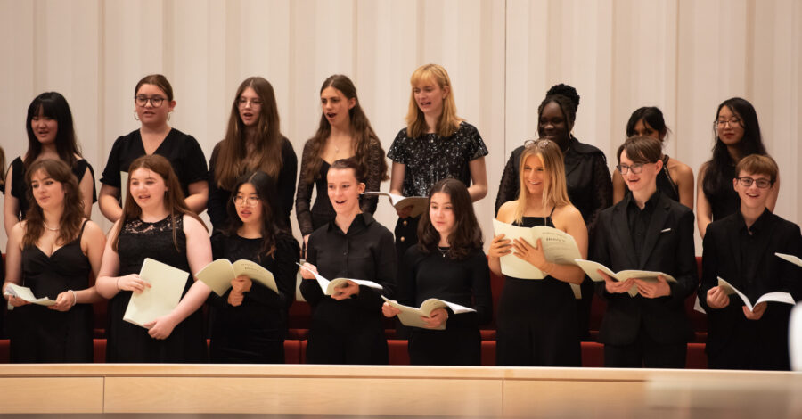 A group of young people dressed in black, singing.
