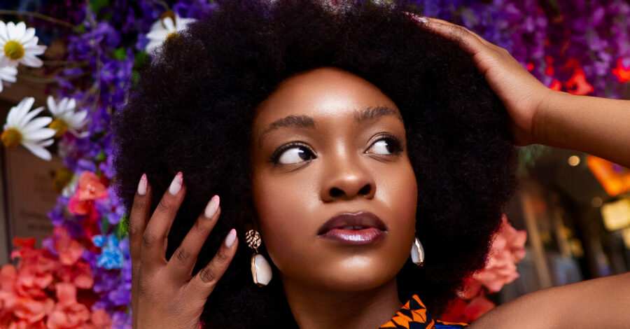 A woman with afro hair in front of a floral background.