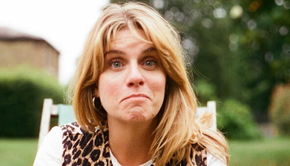 Writer Georgie Jones sat outside on a white chair pulling a confused and intriguing face.