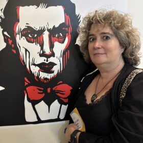 A woman standing next to a picture of a vampire.
