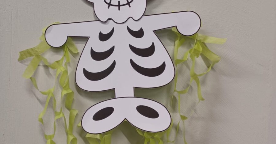 A skeleton made out of paper, wearing a black, green and red hat.