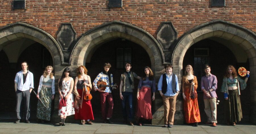 The Manchester Troubadours stood in a line in front of three brick archways on a building.