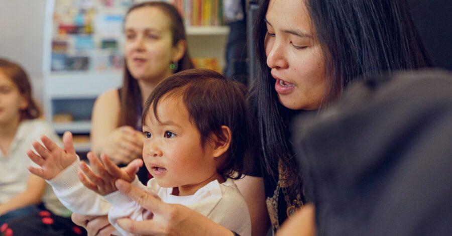 A mother and toddler enjoying a group activity at Z-arts, surrounded by other children and parents in a playful, creative setting.