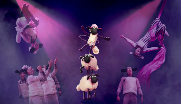 An illustration of three sheep stacked on top of one another on a stage, as performers perform somersaults on each side of them.,