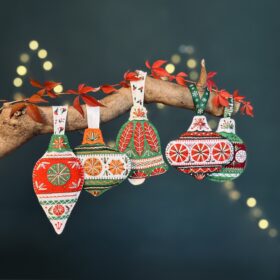 Handcrafted red, green and white fabric Christmas decorations hanging from a branch.