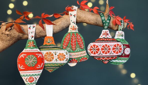 Handcrafted red, green and white fabric Christmas decorations hanging from a branch.
