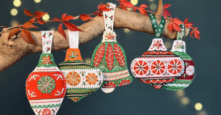 Handcrafted red, green and white fabric Christmas decorations hanging from a branch.