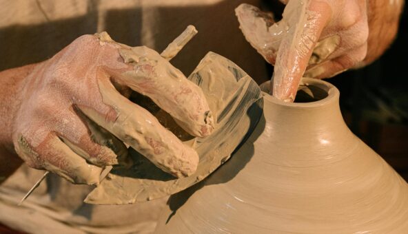 A person making a clay pot on a pottery wheel.