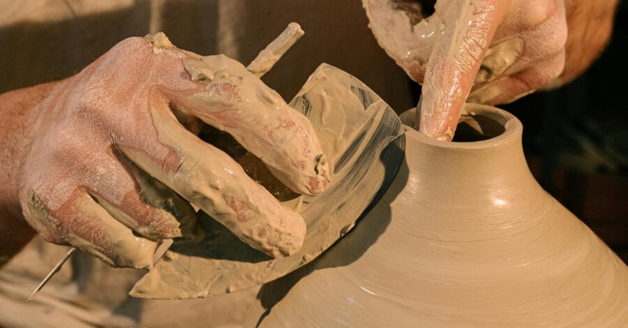 A person making a clay pot on a pottery wheel.