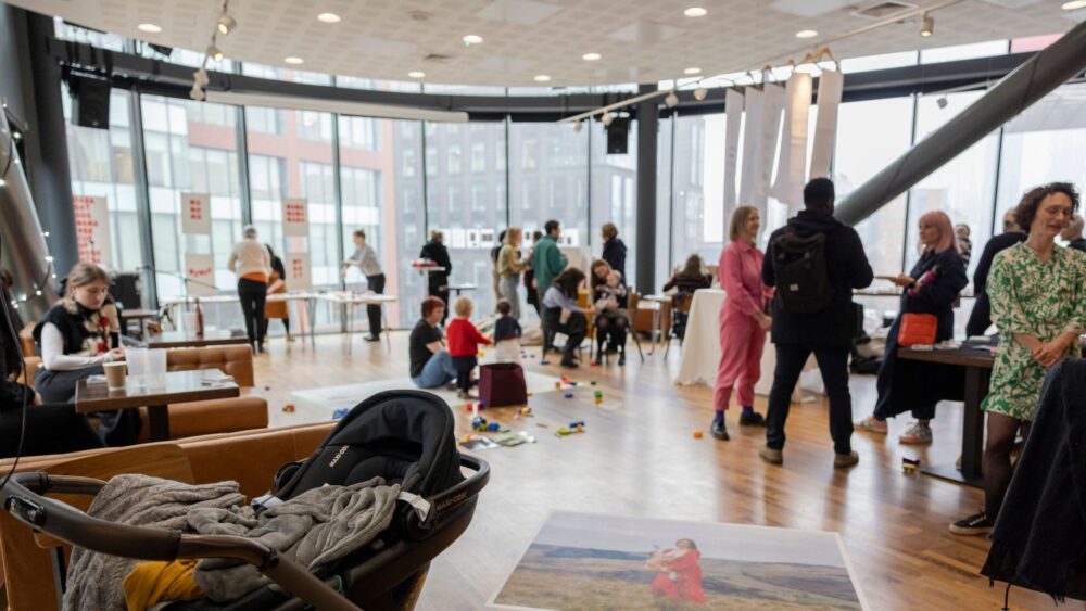 A group of people taking part in a workshop in a large, bright room with big windows.
