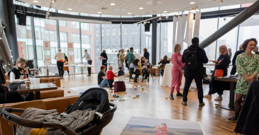 A group of people taking part in a workshop in a large, bright room with big windows.