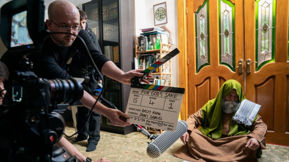 A film set where one person is holding a clackerboard, and another person is sat on the ground waiting for the filming to start.