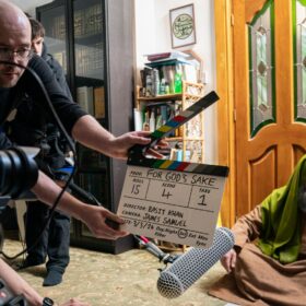 A film set where one person is holding a clackerboard, and another person is sat on the ground waiting for the filming to start.