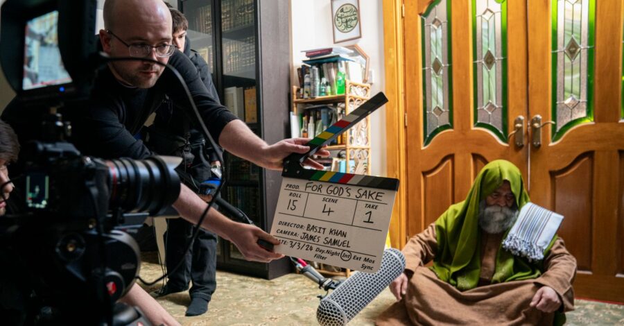 A film set where one person is holding a clackerboard, and another person is sat on the ground waiting for the filming to start.