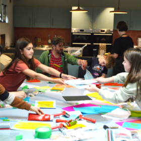 A group of children sitting at a long table and doing crafts.