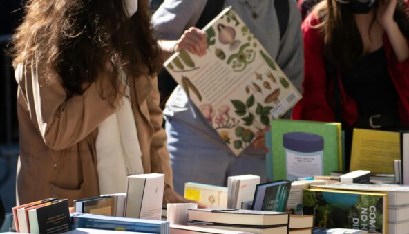 People looking at a table full of different sized books.