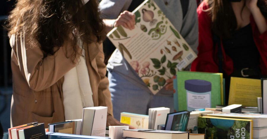 People looking at a table full of different sized books.