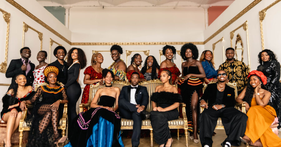 Black creatives in smart attire standing and seated in a lavish ballroom.