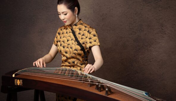 A musician playing the guzheng, a traditional Chinese musical instrument.