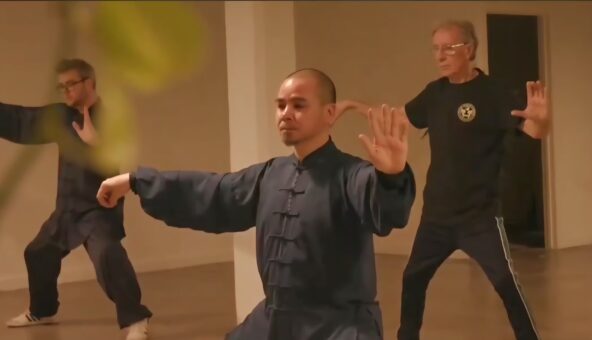3 adults practicing Qigong in a studio.