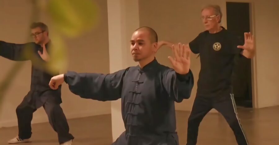 3 adults practicing Qigong in a studio.