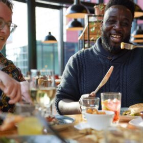 Two people sat at a table enjoying dinner together.