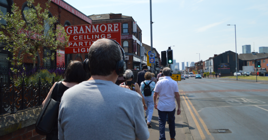 People walking alongside Cheetham Hill Road, wearing headphones