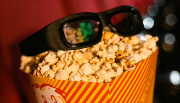 A bag of popcorn with a pair of glasses lying on top.