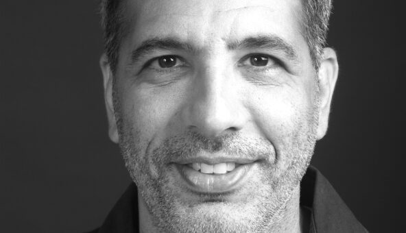 A black and white portrait photograph of Yotam Ottolenghi