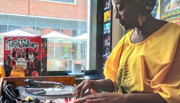 A woman wearing yellow clothes with her hands on a DJ mixing deck.