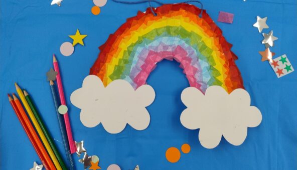 A paper rainbow, star-shaped stickers and some coloured pencils lying on a blue table.