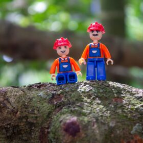 Two Lego figures stood on a tree branch.
