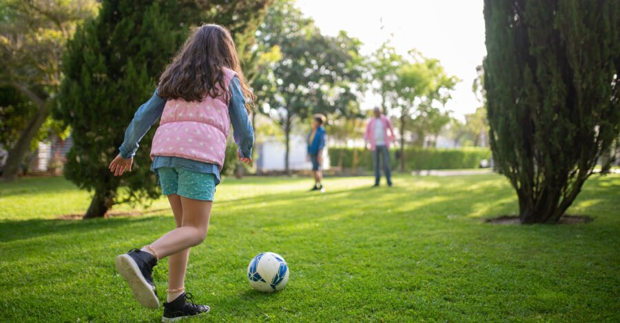 A girl with a football at her feet on a grassy pitch.